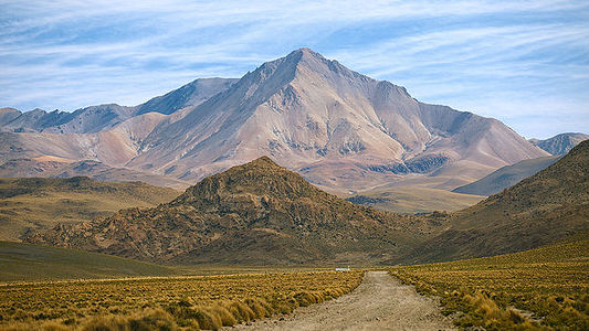 This captivating image leads the viewer along a dusty trail towards the soaring peaks of the Bolivian Andes. The mountain’s stratified colors from mineral deposits create a stunning visual gradient, contrasting with the rough textures of the surrounding landscape. The road, a symbol of adventure, invites one to explore the untamed beauty of Bolivia’s high-altitude wilderness.