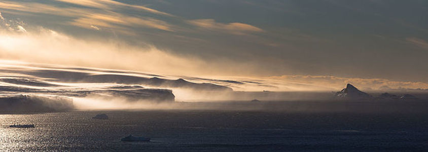 he raw power of nature is on full display in this evocative image, where strong winds whip up a snowstorm over the Arctic tundra. The sun’s rays struggle through the swirling snow, creating a dynamic interplay of light and shadow. This photograph captures the untamed spirit of the Arctic wilderness, highlighting the beauty of a land shaped by the elements.