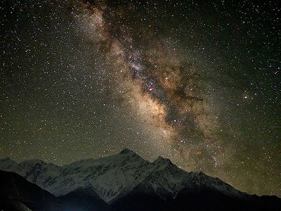 Annapurna majestic peaks reach for the stars in this breathtaking nighttime capture. The Milky Way unfurls its stellar majesty above, a sparkling river of light that highlights the eternal dance between Earth and cosmos.