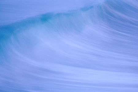This image captures the dynamic essence of a cresting wave in a blurred motion. The cool blue tones convey the ocean’s power and grace, while the fluid lines illustrate the wave’s fleeting beauty in a moment frozen in time.
