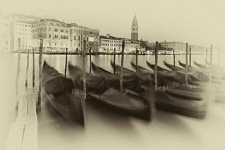 Venice’s gondolas sway gently in the waters, captured in a timeless sepia photograph that evokes the historic charm of this iconic city.