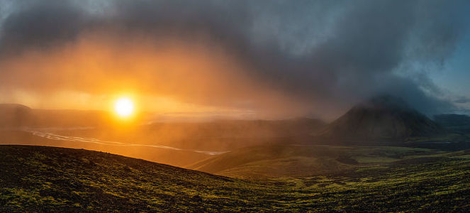 Станьте свидетелем безмятежной красоты исландского утра в этой панорамной фотографии, где восходящее солнце пробивается сквозь утренний туман, озаряя высокогорья сияющим светом. Ранний свет раскрывает контуры и текстуры ландшафта, а одинокая гора стоит на страже этой спокойной сцены. Этот момент улавливает суть жесткого, но прекрасного рельефа Исландии, предлагая зрителю взглянуть на естественное великолепие страны на рассвете.
