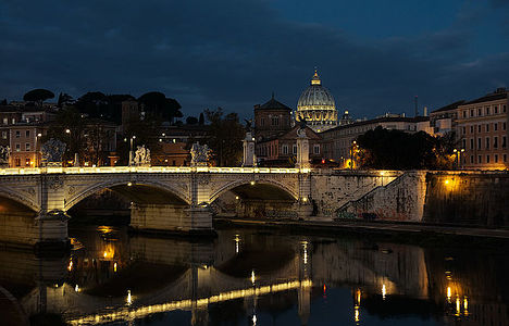 Enjoy the peaceful evening ambiance along the Tiber River, with the Ponte Sant’Angelo leading to the illuminated St. Peter’s Basilica.Rome.