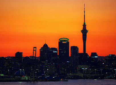 Behold the striking silhouette of Auckland’s skyline as the Sky Tower stands tall against the vibrant hues of a stunning sunset.