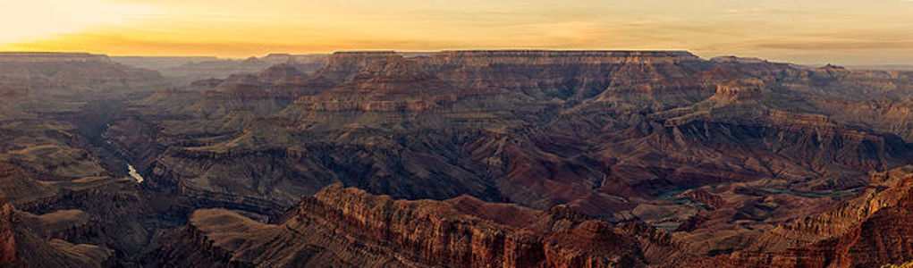 This captivating image features the sweeping vistas of the Grand Canyon bathed in the golden light of sunset, highlighting the deep gorges and complex layers of geology.