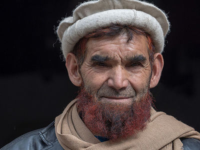 This powerful portrait from Pakistan captures the weathered face of an elder, his gaze reflecting a lifetime of stories. The traditional hat and the warmth of his scarf highlight his cultural heritage. The intricate details of his facial lines and the striking hue of his beard tell tales of the rugged life in Pakistan’s landscapes. It’s a humanizing snapshot that beautifully conveys wisdom and resilience.